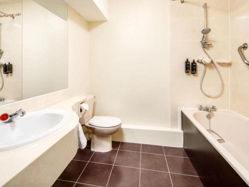 a bathroom with a toilet and a tub and a sink at Mercure Bolton Georgian House Hotel in Bolton