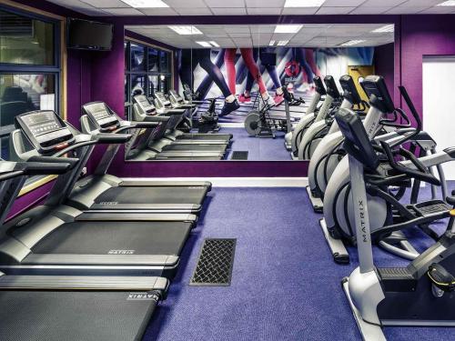 a gym with rows of treadmills and machines at Mercure Chester Abbots Well Hotel in Chester
