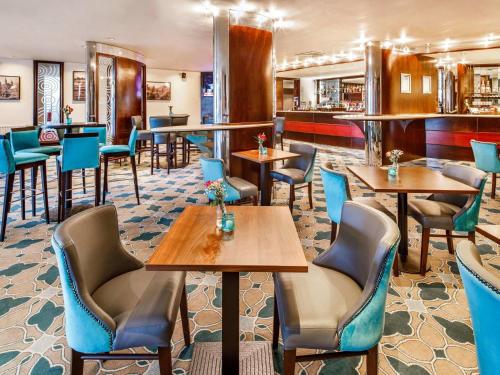 a restaurant with tables and chairs and a bar at Mercure Chester Abbots Well Hotel in Chester