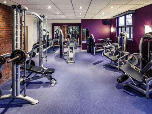 a gym with rows of treadmills and machines at Mercure Chester Abbots Well Hotel in Chester