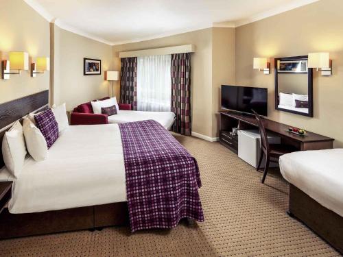 a hotel room with two beds and a flat screen tv at Mercure Chester Abbots Well Hotel in Chester