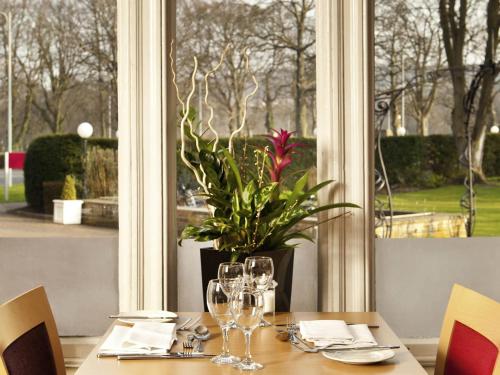 a table with wine glasses and a potted plant at Mercure Bradford, Bankfield Hotel in Bradford