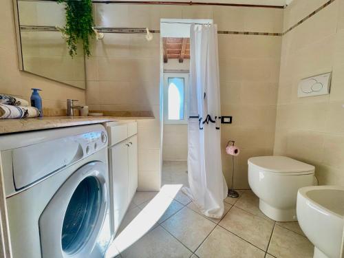 Un baño con lavadora y un inodoro. en Monolocale sul fiume, en Calcinaia
