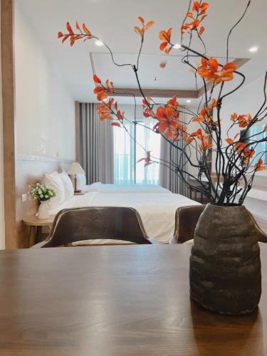 a vase with flowers on a table in a bedroom at Seafront Apartment TMS Quy Nhơn in Quy Nhon