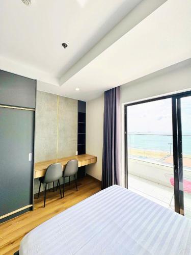 a bedroom with a bed and a desk with a view of the ocean at Seafront Apartment TMS Quy Nhơn in Quy Nhon