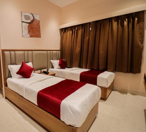 two beds with red pillows in a hotel room at Ascent Star Inn in Mumbai
