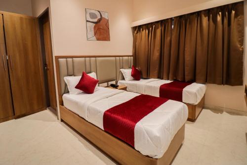 two beds in a hotel room with red pillows at Ascent Star Inn in Mumbai
