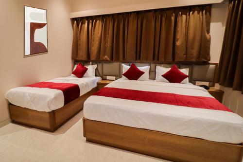 two beds in a hotel room with red pillows at Ascent Star Inn in Mumbai