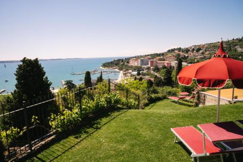 a patio with an umbrella and a view of the ocean at Villa Bellevue Portoroz-Portorose in Portorož