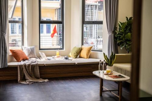 Sofá en habitación con 2 ventanas en The Amethyst Nest Hanoi-Tranquil Stay with Rooftop & Coffee Shop-Near Old Quarter, en Hanói