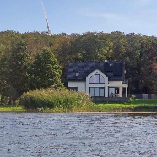 a white house on the shore of a body of water at Apartamenty Zagórze 55 in Zagórze