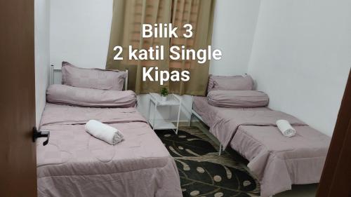 two beds in a room with the words blitz kauri single kips at D'Raudhah Homestay Binjai Kemaman 