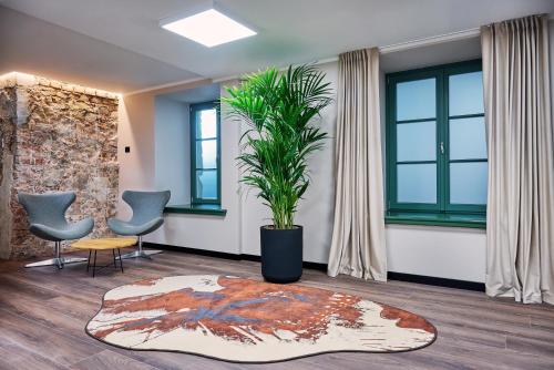 a living room with a potted plant and chairs at Pullman Riga Old Town in Rīga
