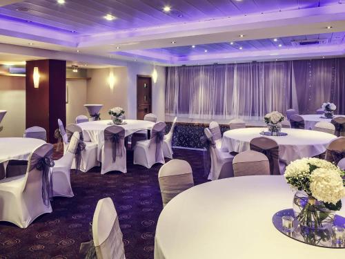 a banquet hall with white tables and chairs and flowers at Mercure Glasgow City Hotel in Glasgow