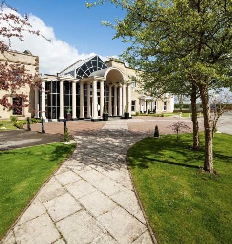 a large white building with a tree in front of it at Mercure York Fairfield Manor Hotel in York