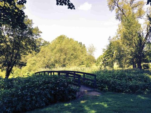 a wooden bridge in a field with trees and grass at Mercure York Fairfield Manor Hotel in York