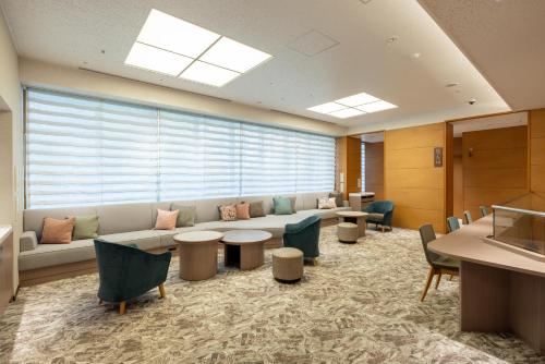 a waiting room with a couch and tables and chairs at Richmond Hotel Utsunomiya-ekimae Annex in Utsunomiya