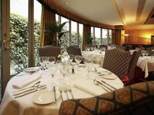 a table in a restaurant with white tables and chairs at Mercure York Fairfield Manor Hotel in York