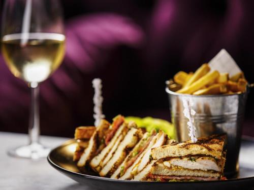 a plate with a sandwich and french fries and a glass of wine at Mercure York Fairfield Manor Hotel in York