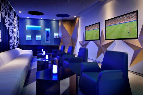 a room with couches and chairs and a television at Southern Sun Abu Dhabi in Abu Dhabi