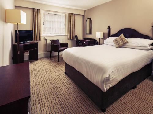 a hotel room with a large bed and a television at Mercure Perth Hotel in Perth
