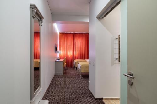 a hallway with a room with two beds and a mirror at Hotel Sinchronas in Telšiai