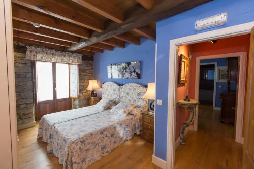 a bedroom with a bed with blue walls and wooden floors at Hotel Rural Casa Xusto in La Caridad