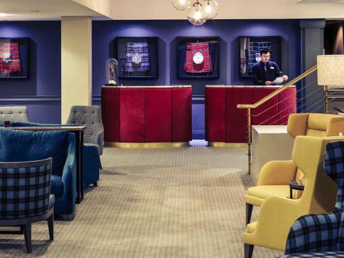 a man standing at a counter in a waiting room at Mercure Inverness Hotel in Inverness