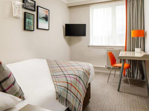 a hotel room with a bed and a desk and a window at Mercure Inverness Hotel in Inverness