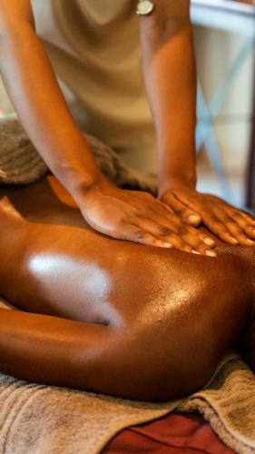 a woman sitting on a towel with her hands on her back at The David Livingstone Safari Lodge & Spa in Livingstone