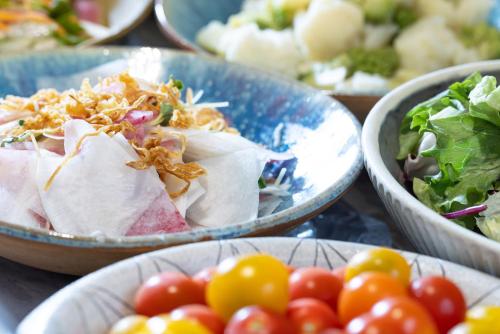 a table topped with bowls of salad and tomatoes at Richmond Hotel Utsunomiya-ekimae Annex in Utsunomiya