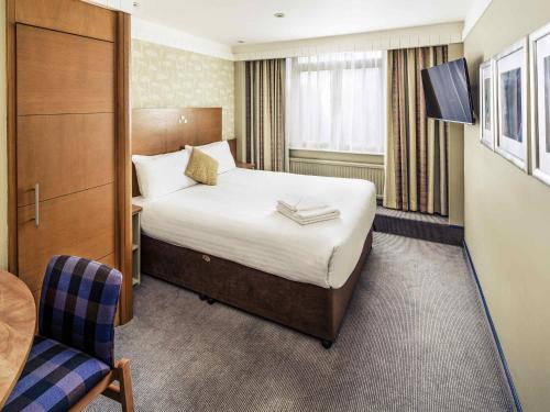 a hotel room with a bed and a chair at Mercure Maidstone Great Danes Hotel in Maidstone