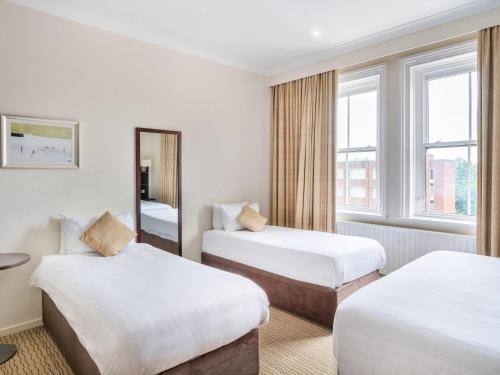 a hotel room with two beds and a mirror at Mercure Maidstone Great Danes Hotel in Maidstone
