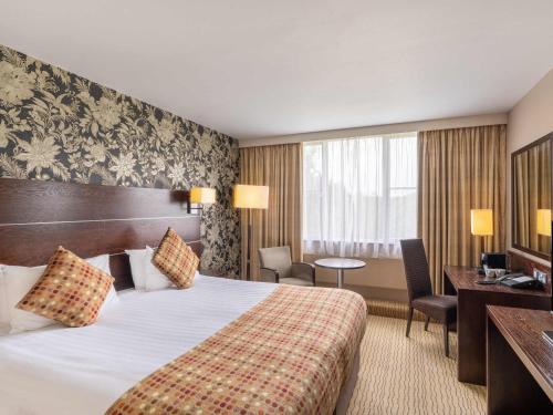 a hotel room with a bed and a desk at Mercure Maidstone Great Danes Hotel in Maidstone