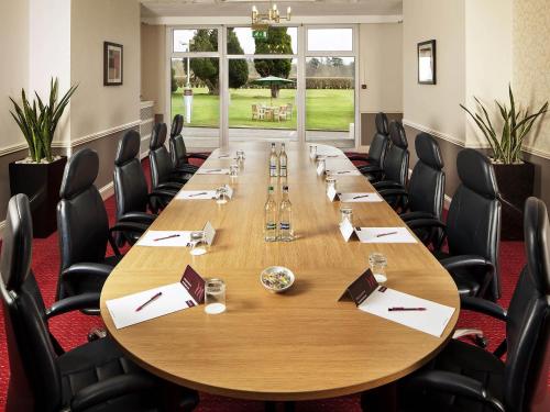 a conference room with a large wooden table and chairs at Mercure Maidstone Great Danes Hotel in Maidstone