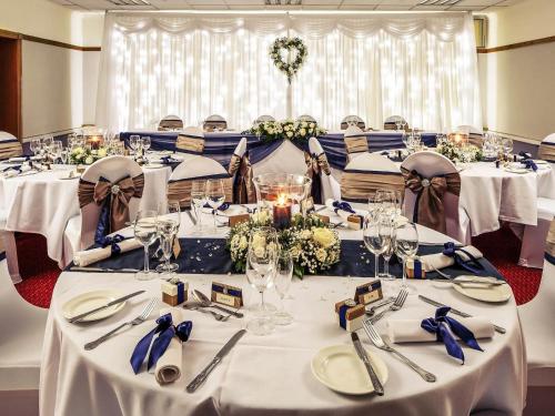 a set of tables in a room with white tablecloths at Mercure Maidstone Great Danes Hotel in Maidstone