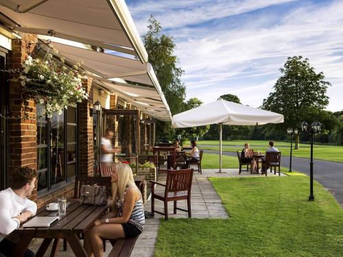 a group of people sitting at a table under an umbrella at Mercure Maidstone Great Danes Hotel in Maidstone