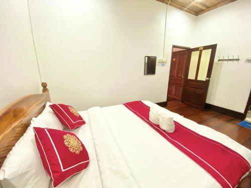 a bed with red and white pillows on it at Villa That Luang Legend in Luang Prabang