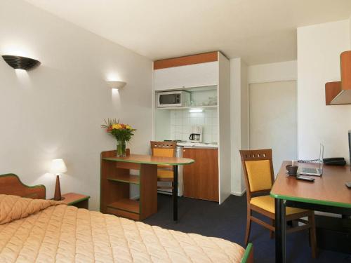 a hotel room with a bed and a table and a kitchen at Aparthotel Adagio Access La Défense - Léonard De Vinci in Courbevoie