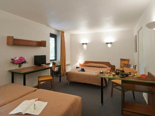 a hotel room with two beds and a desk at Aparthotel Adagio Access La Défense - Léonard De Vinci in Courbevoie