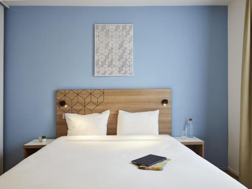 a bedroom with a white bed with a blue wall at Aparthotel Adagio Access Paris Quai d'Ivry in Ivry-sur-Seine