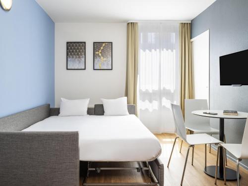 a hotel room with a white bed and a table at Aparthotel Adagio Access Paris Quai d'Ivry in Ivry-sur-Seine