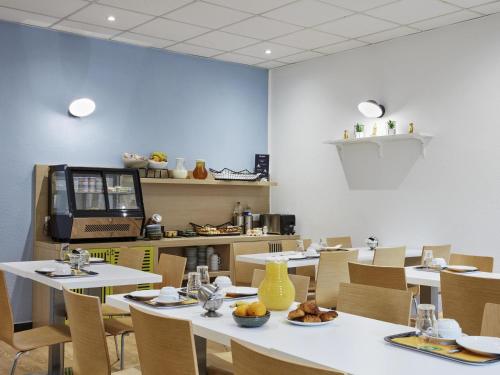 a dining room with tables and chairs with food on them at Aparthotel Adagio Access Paris Quai d'Ivry in Ivry-sur-Seine