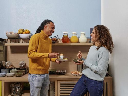 a man and a woman holding a plate in a kitchen at Aparthotel Adagio Access Paris Quai d'Ivry in Ivry-sur-Seine