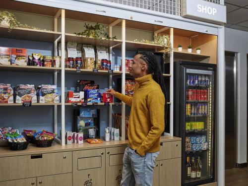 a man standing in front of a store shelf at Aparthotel Adagio Access Paris Quai d'Ivry in Ivry-sur-Seine