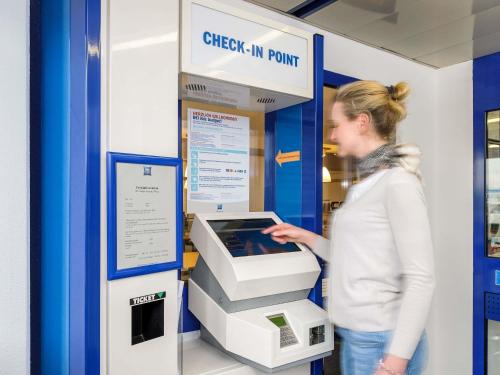 a woman is standing next to an atm machine at Ibis budget Osnabrück City in Osnabrück