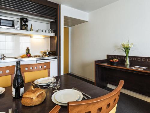 a dining room with a table with a bottle of wine at Aparthotel Adagio Access Toulouse Jolimont in Toulouse
