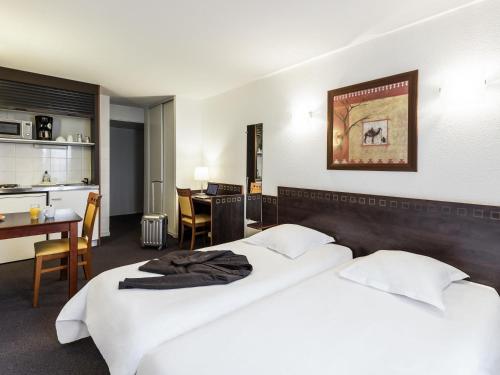 a hotel room with two beds and a kitchen at Aparthotel Adagio Access Toulouse Jolimont in Toulouse