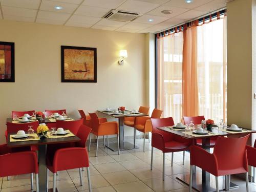 a dining room with tables and red chairs at Aparthotel Adagio Access Toulouse Jolimont in Toulouse