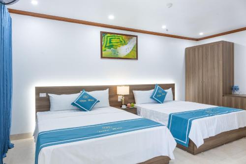 Văn LâmにあるDiện Hoa Homestayの白と青の部屋にベッドが2つ